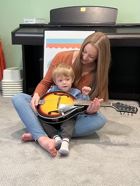 Teacher and young child exploring a string instrument together